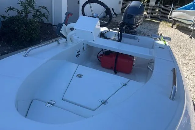 Slide: The Image of 2024 Rigid Boats 10 Sport, white interior, outboard motor, red fuel tank, parked outdoors. - 14