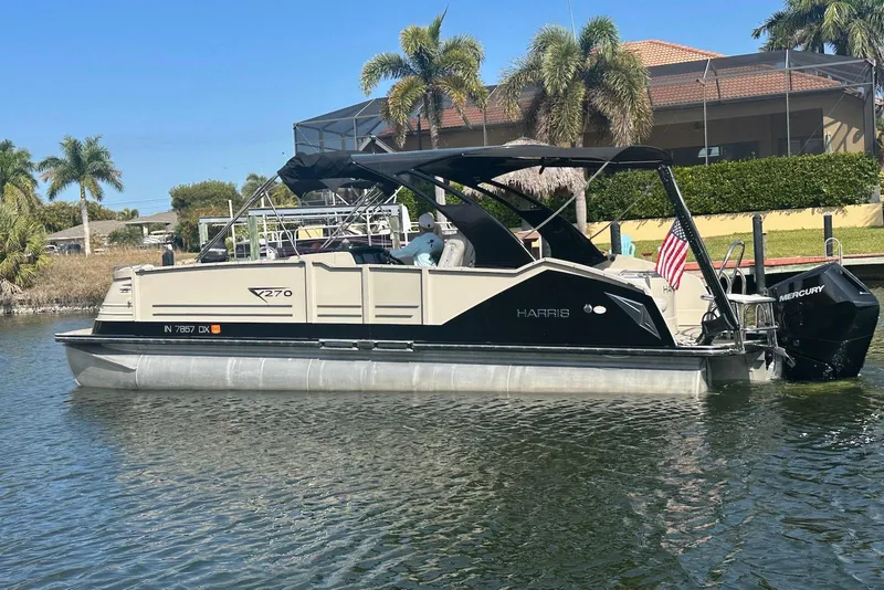 The Image of 2017 Harris V270 pontoon boat on water, palm trees in background, American flag displayed. - 0