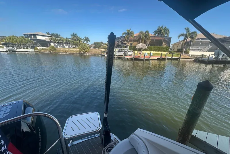 Slide: The Image of Pontoon boat on a serene canal, Harris V270, 2017 model, with waterfront homes. - 16