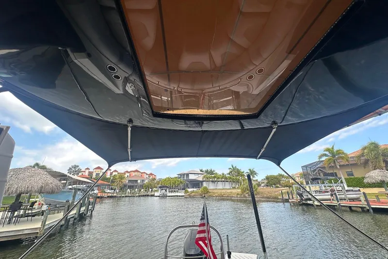 Slide: The Image of 2017 Harris V270 boat with canopy, docked in a scenic waterfront area. - 17