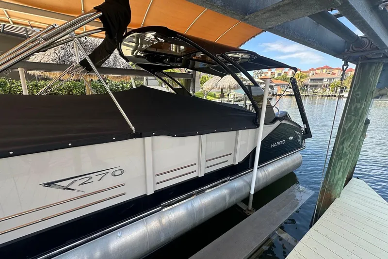 Slide: The Image of 2017 Harris V270 pontoon boat docked under a canopy on a sunny day. - 21