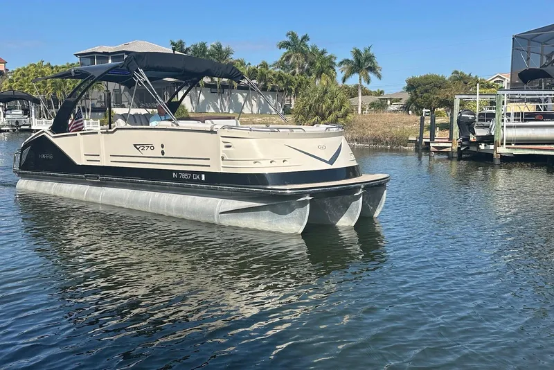Slide: The Image of 2017 Harris V270 pontoon boat on calm water, surrounded by palm trees and docks. - 3