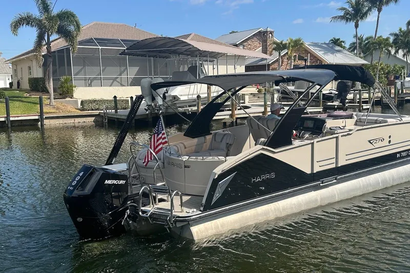 Slide: The Image of 2017 Harris V270 pontoon boat docked in a sunny waterfront setting. - 4