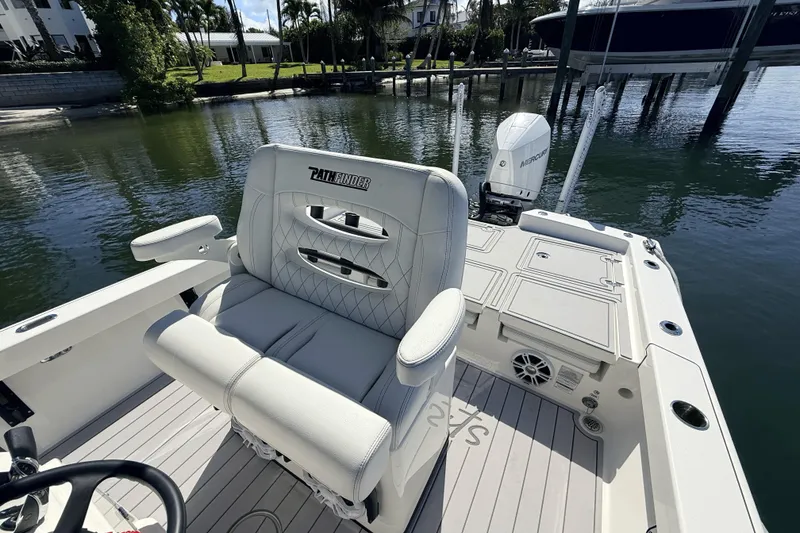 Slide: The Image of 2023 Pathfinder 2600 TRS boat interior with seating and motor, docked by water. - 10