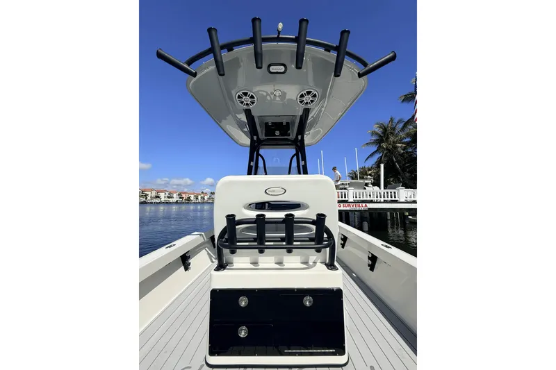 Slide: The Image of 2023 Pathfinder 2600 TRS boat interior with rod holders and T-top, docked by waterfront. - 14
