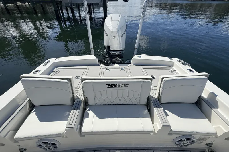 Slide: The Image of 2023 Pathfinder 2600 TRS boat with cushioned seating and outboard motor on calm water. - 20