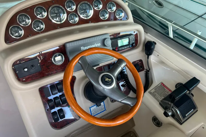 Slide: The Image of 1999 Sea Ray 290 Sundancer helm with wood steering wheel and navigation instruments. - 13