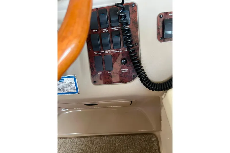 Slide: The Image of Control panel of a 1999 Sea Ray 290 Sundancer boat with switches and coiled cord. - 17