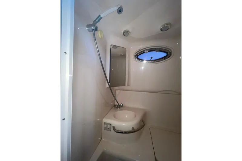 Slide: The Image of 1999 Sea Ray 290 Sundancer bathroom with shower, sink, and porthole window. - 24
