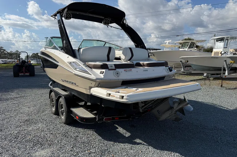Slide: The Image of 2016 Regal 2300 Bowrider boat on trailer, parked outdoors under a cloudy sky. - 2