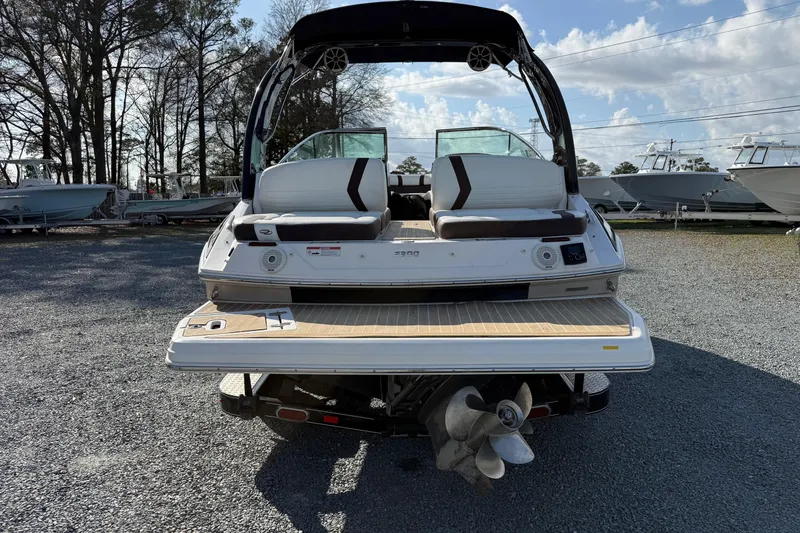 Slide: The Image of 2016 Regal 2300 Bowrider boat, rear view, parked on gravel lot with trees in background. - 3