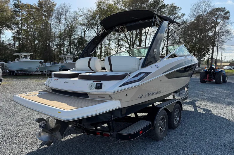Slide: The Image of 2016 Regal 2300 Bowrider boat on trailer, parked outdoors with trees in background. - 4
