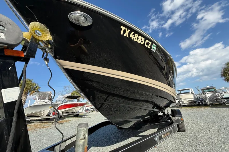 Slide: The Image of 2016 Regal 2300 Bowrider boat on trailer, parked in marina under blue sky. - 7