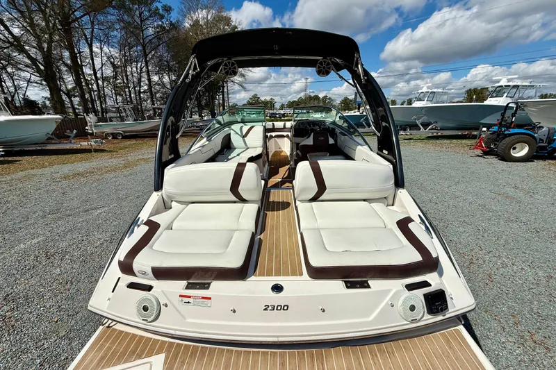 Slide: The Image of 2016 Regal 2300 Bowrider boat with white seating, parked outdoors under a cloudy sky. - 9
