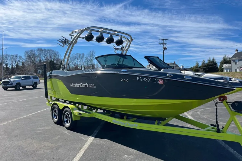 Slide: The Image of 2017 MasterCraft NXT22 boat on trailer in parking lot under blue sky. - 3