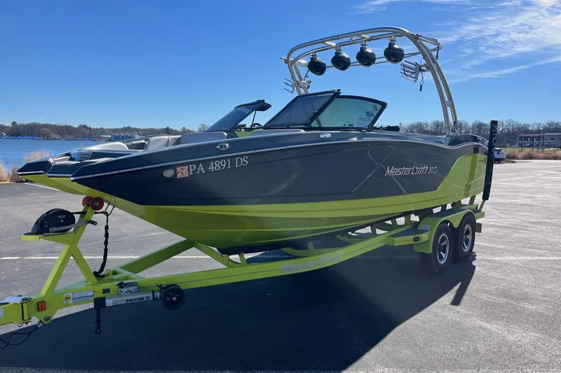 Slide: The Image of 2017 MasterCraft NXT22 boat on trailer, parked near a lake under clear blue sky. - 5
