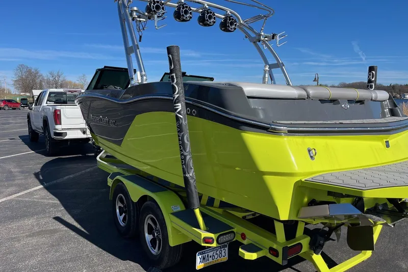 Slide: The Image of 2017 MasterCraft NXT22 boat in bright green on a trailer, parked in a lot. - 8