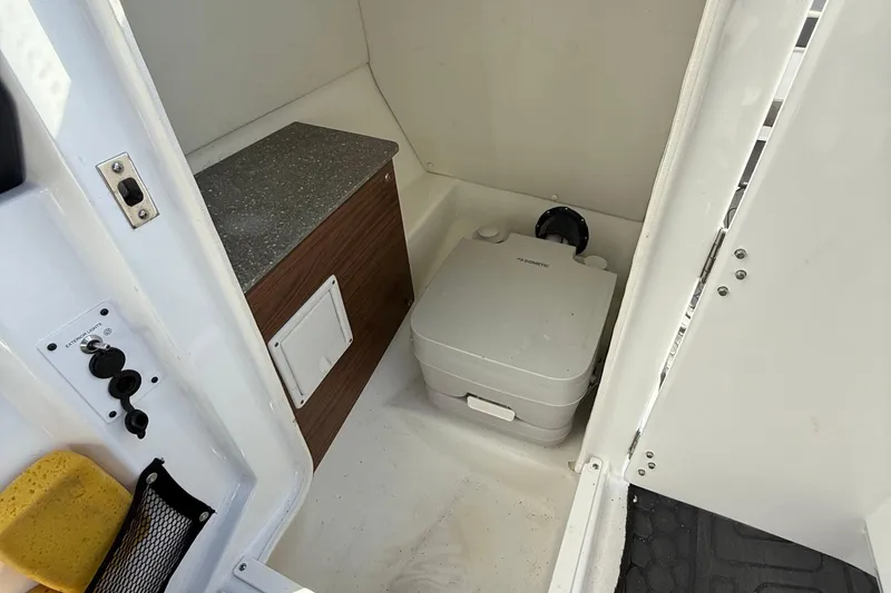 Slide: The Image of 2021 Scarab 255 ID boat interior with compact marine toilet and storage area. - 16