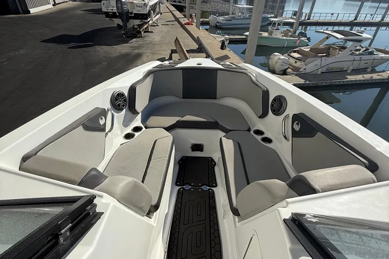 Slide: The Image of 2021 Scarab 255 ID boat interior with cushioned seating and cup holders at a marina. - 9