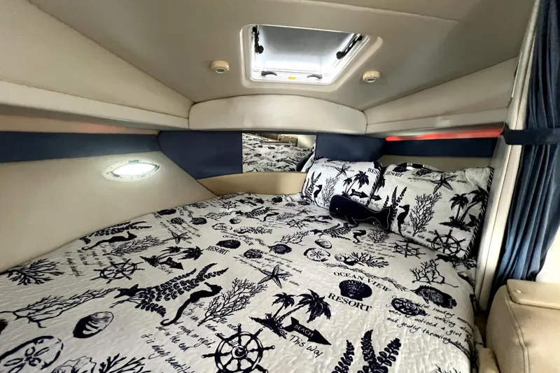 Slide: The Image of Cozy cabin interior of 2007 Bayliner 305 with nautical-themed bedding and porthole window. - 14