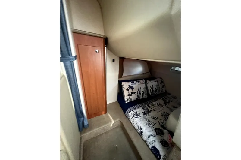 Slide: The Image of 2007 Bayliner 305 cabin interior with nautical-themed bedding and wooden storage. - 16