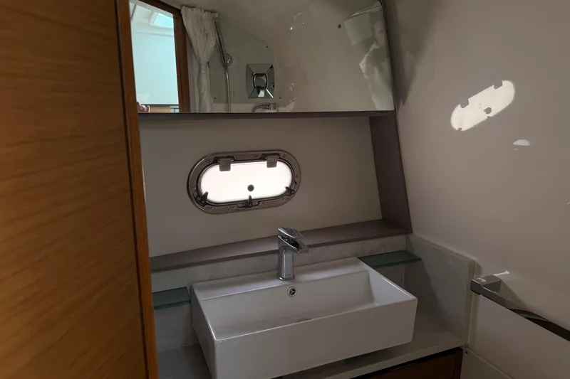 Slide: The Image of Luxurious bathroom interior of 2022 Tiara Yachts 38 LS with modern sink and porthole window. - 13