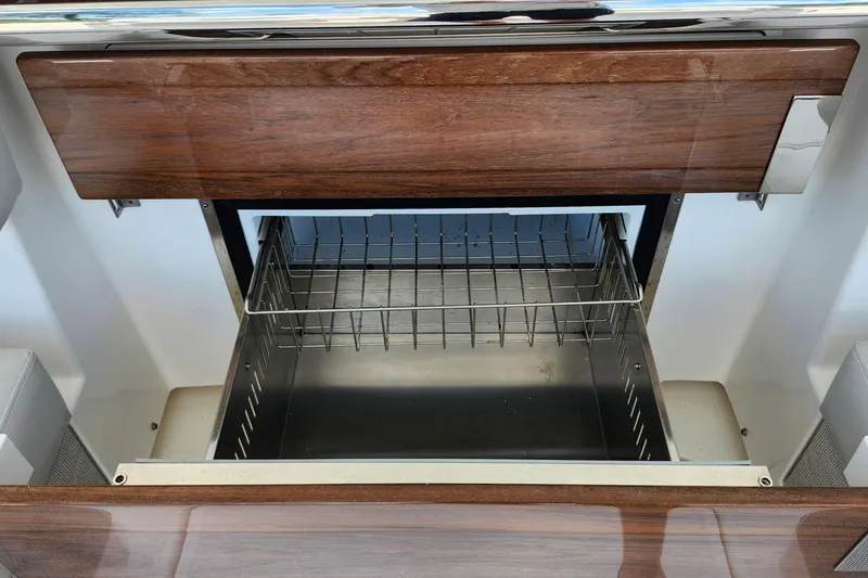 Slide: The Image of Open storage compartment on 2022 Tiara Yachts 38 LS, featuring wood finish and metal rack. - 51