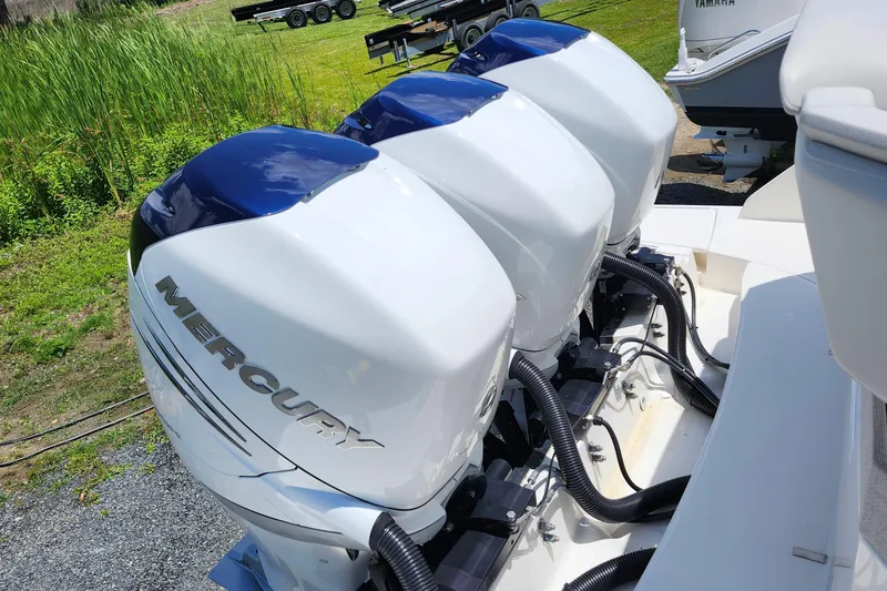 Slide: The Image of Triple Mercury outboard engines on a 2022 Tiara Yachts 38 LS, parked on a grassy area. - 57
