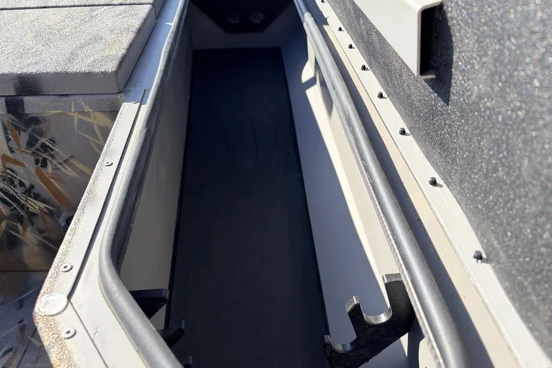 Slide: The Image of 2025 Ranger RB210 boat interior storage compartment with textured surfaces and secure railings. - 25
