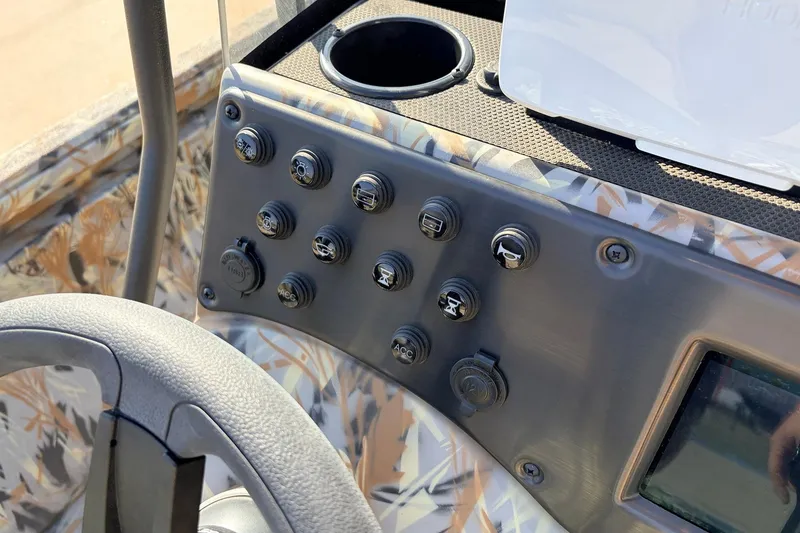 Slide: The Image of Control panel of 2025 Ranger RB210 boat with various switches and cup holder. - 36