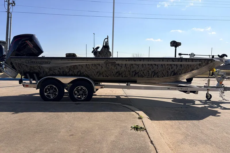 Slide: The Image of 2025 Ranger RB210 boat on trailer, camo design, parked outdoors under clear sky. - 4