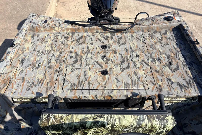 Slide: The Image of 2025 Ranger RB210 boat with camouflage deck design and motor, parked on concrete. - 48