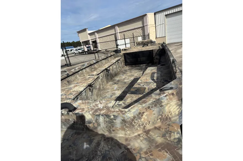 Slide: The Image of 2023 Excel 1754 Shallow Water F4 boat with camouflage design, parked outdoors. - 18