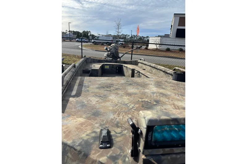 Slide: The Image of 2023 Excel 1754 Shallow Water F4 boat with camouflage design, parked outdoors. - 21