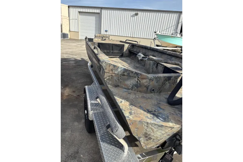 Slide: The Image of 2023 Excel 1754 Shallow Water F4 boat on trailer, camo design, outdoor setting. - 22