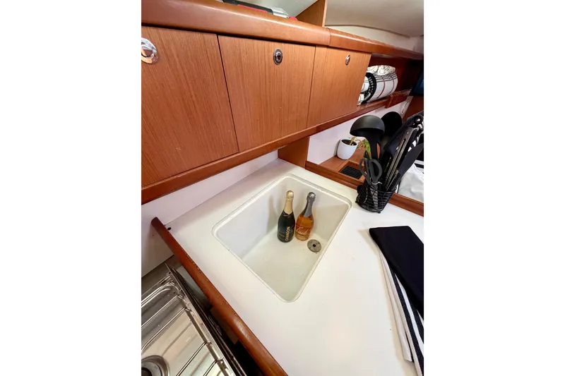 Slide: The Image of Galley sink area in 2008 Beneteau Oceanis 37 sailboat with utensils and bottles. - 28