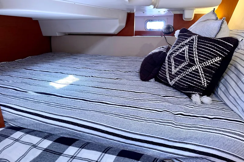 Slide: The Image of Cozy cabin interior of 2008 Beneteau Oceanis 37 with striped bedding and decorative pillows. - 29