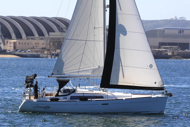 Slide: The Image of 2008 Beneteau Oceanis 37 sailboat on water, sails up, near industrial buildings. - 4