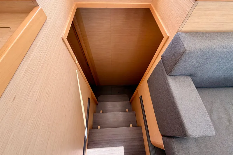 Slide: The Image of Interior stairs of 2017 Lagoon 42 yacht, featuring wooden finish and gray sofa. - 24