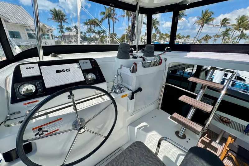 Slide: The Image of 2017 Lagoon 42 yacht cockpit with steering wheel, navigation system, and tropical backdrop. - 6