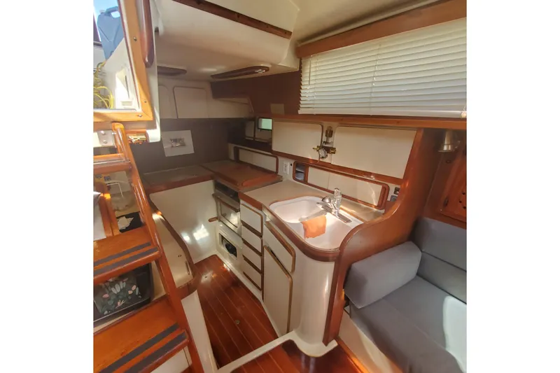 Slide: The Image of 1987 Irwin 38 Mk II yacht interior with wooden cabinetry and compact kitchen area. - 11