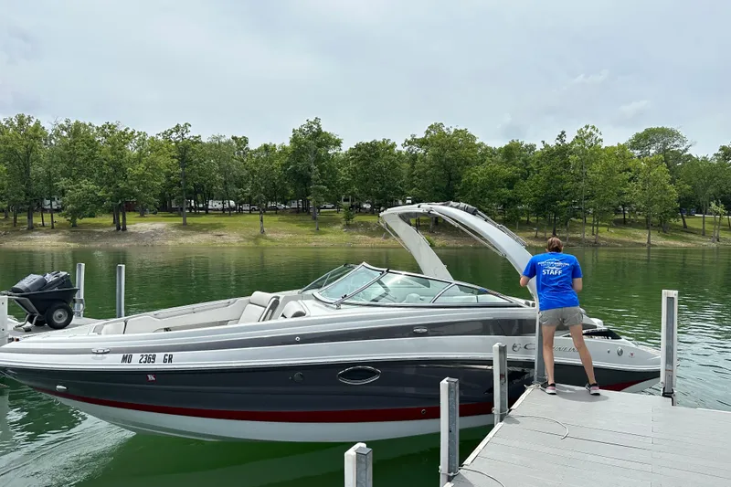 The Image of 2022 Crownline 265 SS boat docked at a serene lakeside with lush greenery. - 0