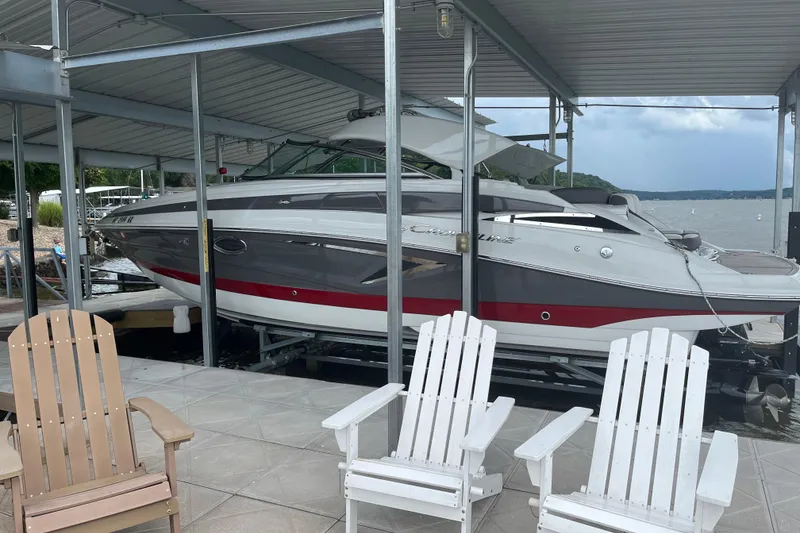 Slide: The Image of 2022 Crownline 265 SS boat docked under a covered marina with lake view. - 2