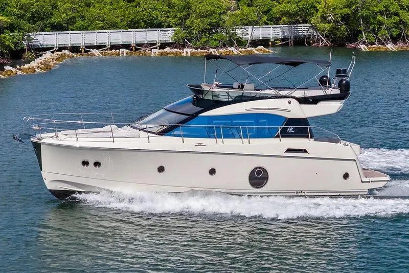 Slide: The Image of 2018 Monte Carlo MC 35 yacht cruising on a serene waterway with lush greenery. - 3