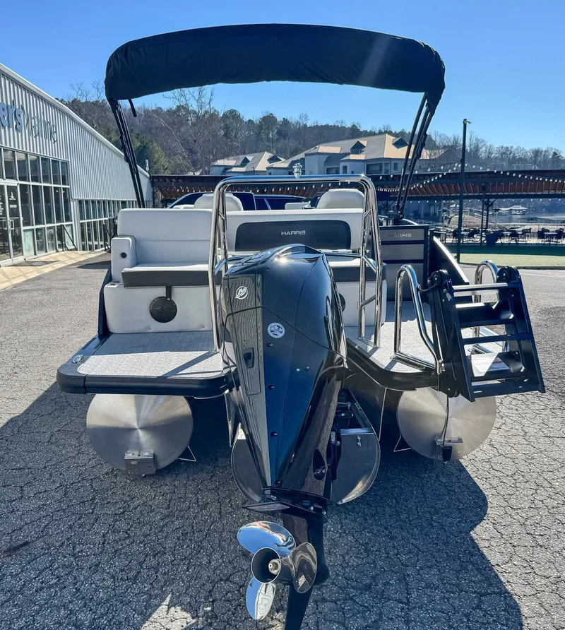 Slide: The Image of 2026 Harris Cruiser 230 SLDH with outboard motor, parked outdoors. - 9