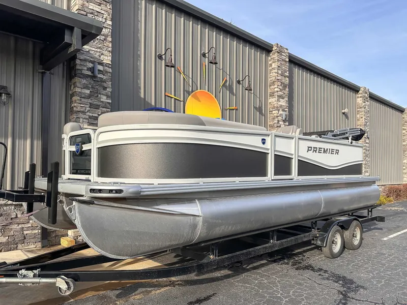 Slide: The Image of 2026 Premier Sunscape 220 RF pontoon boat on trailer outside building. - 3