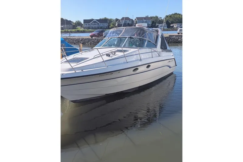 Slide: The Image of 1992 Chaparral Signature 30 boat docked in calm waters, with houses in the background. - 2