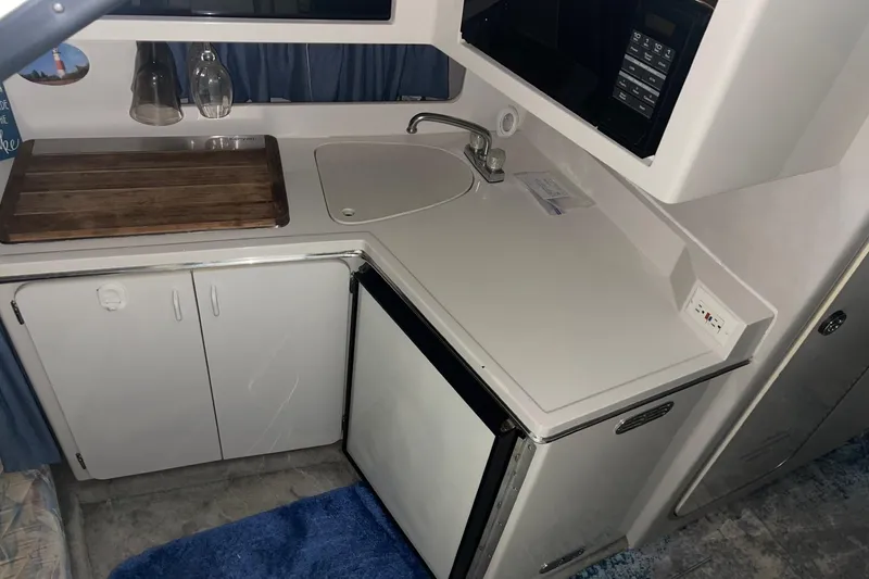 Slide: The Image of 1992 Chaparral Signature 30 boat kitchen with sink, fridge, and microwave. - 22