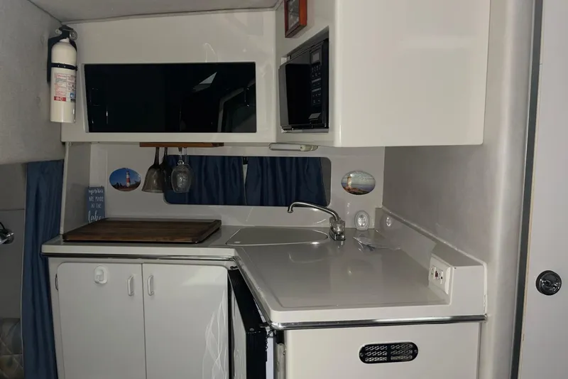 Slide: The Image of 1992 Chaparral Signature 30 boat kitchen with sink, cabinets, and microwave. - 23