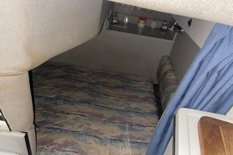 Slide: The Image of 1992 Chaparral Signature 30 cabin interior with bed, blue curtain, and storage shelf. - 26